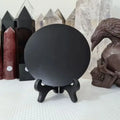 Black crystal ball on a stand with crystals and a skull in the background