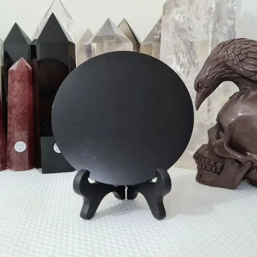 Black crystal ball on a stand with crystals and a skull in the background